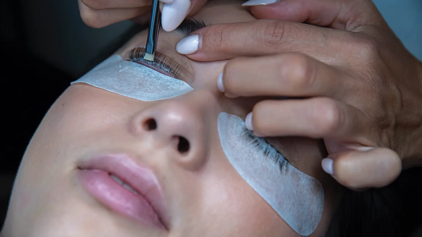 Nahaufnahme einer Wimpernbehandlung mit Bürstchen und Unterlidpads